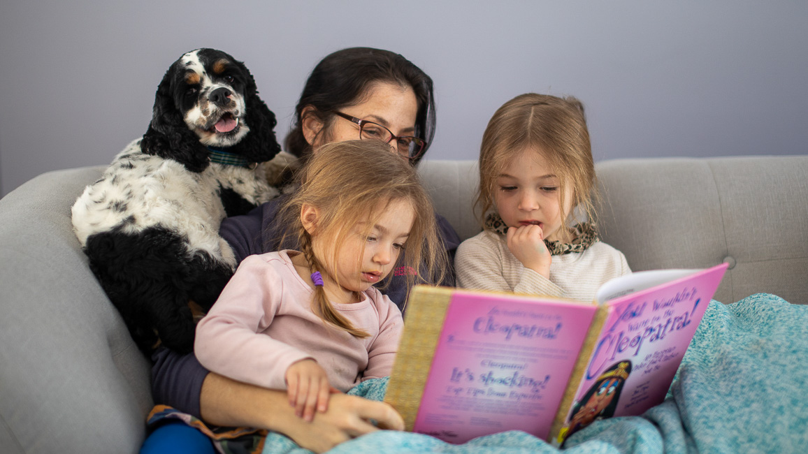 mom with two kids and dog reading a book